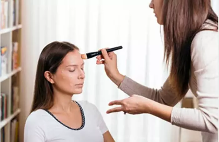 A beautican applying applying face primer to her clients face