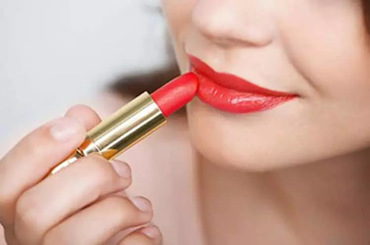 woman applying lipstick to her lips