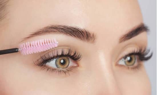 A young lady applying mascara to her eyelashes