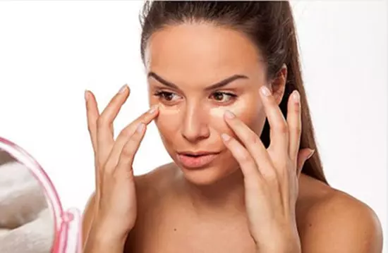 A woman applying foundation to her face.