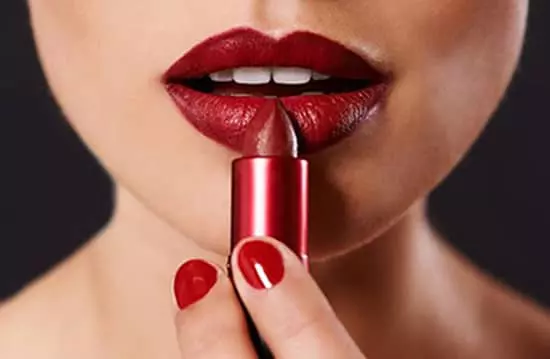 A woman applying lipstick to her lips