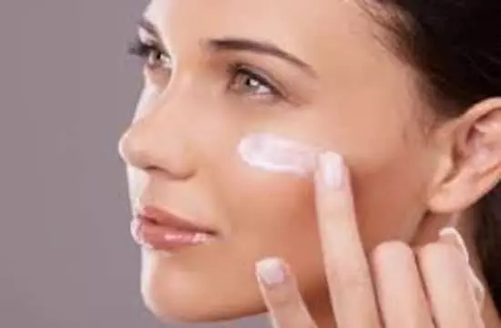 A woman applying eye primer to her eye area