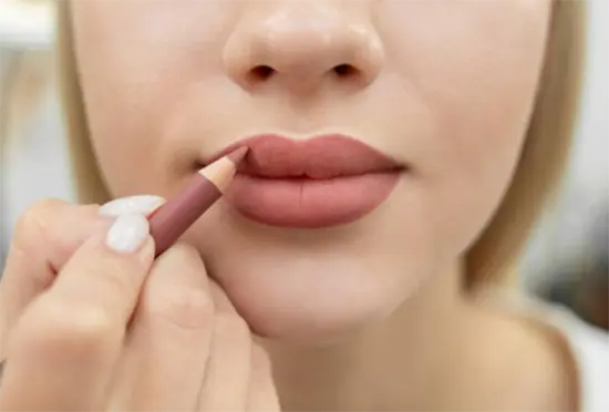 A young woman applying lipliner to her upper lip