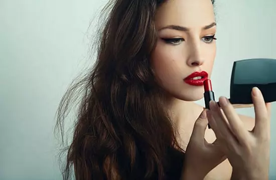 A young woman applying lipstick to her lips