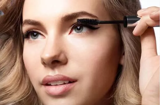 A woman expertly applies mascara with a mascara brush, enhancing her eyelashes with precision